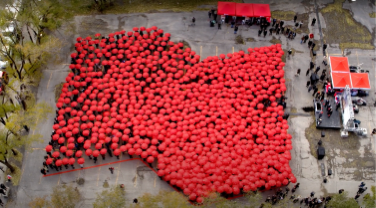Photo from a bird’s eye view of people holding red umbrellas forming the National Bank logo