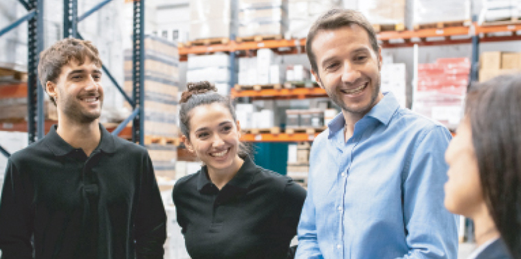 Photo of four people smiling  in a warehouse