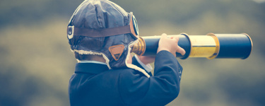 Little boy dressed as a pilot looks through a telescope