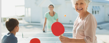 Boy playing ping pong with his mother and grandmother