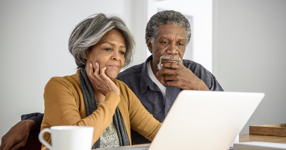 Retired couple deep in thought looking at a laptop