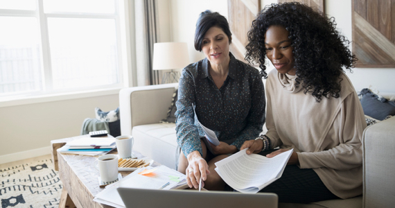 Advisor pointing at a computer screen and woman both sitting on a couch