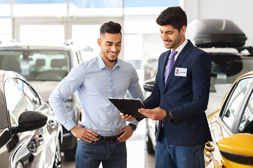 Two men looking at a clipboard in a car showroom