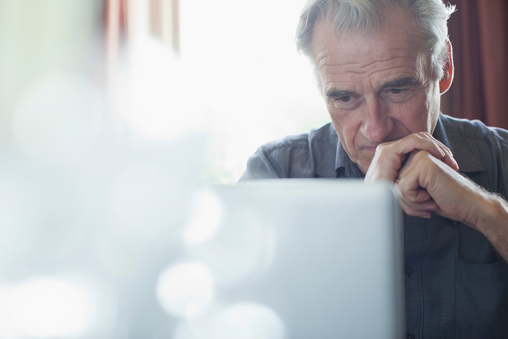 Mature man looking thoughtful in front of his computer