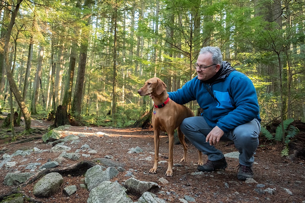 Image of a retired man on a hike in nature with his dog