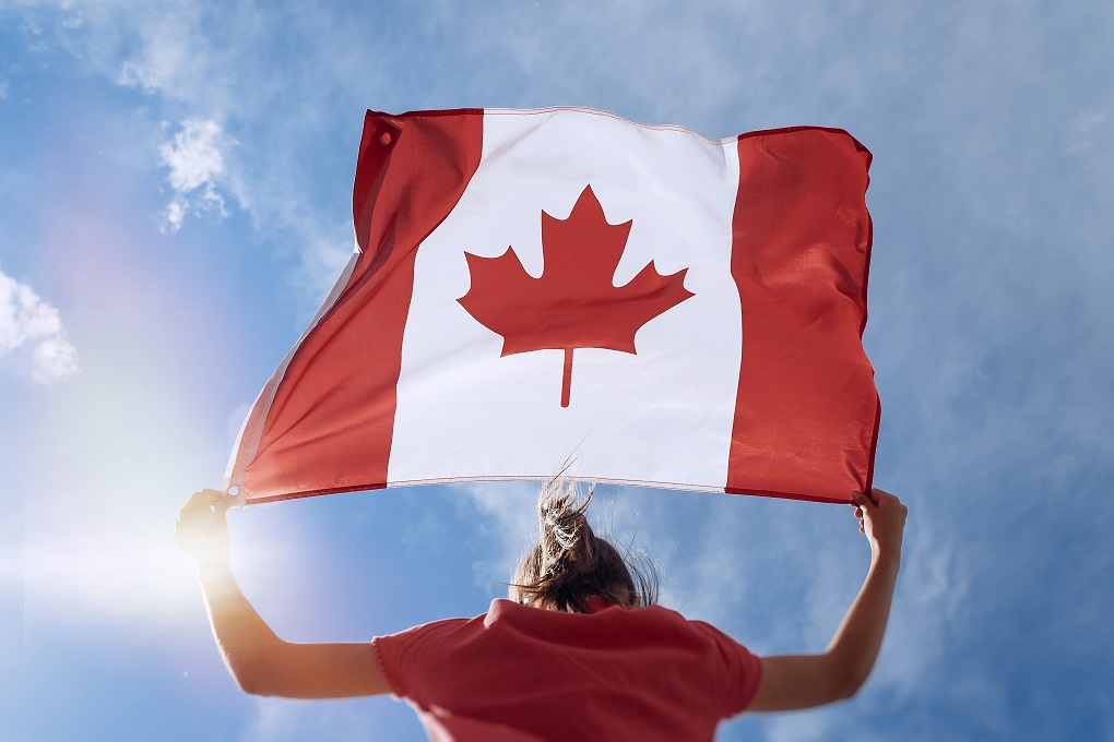 A woman who is a resident of Canada holds a Canadian flag in her hands.