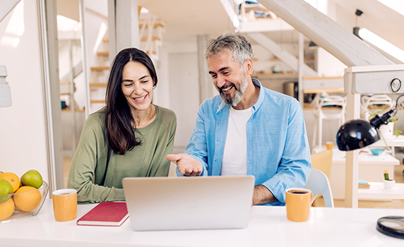 Photo of a man and woman smiling while they look at a computer in an office in Florida 