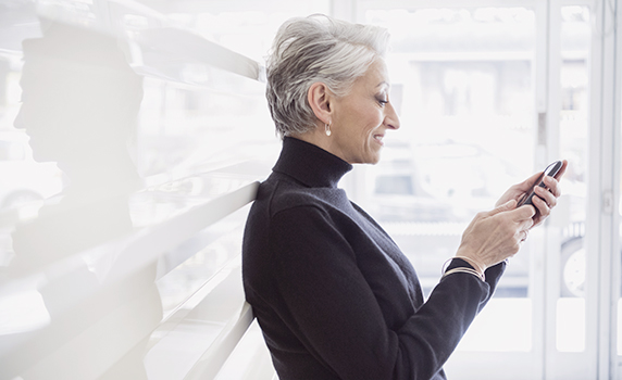 Photo of a smiling woman in a well-lit room checking her smartphone 