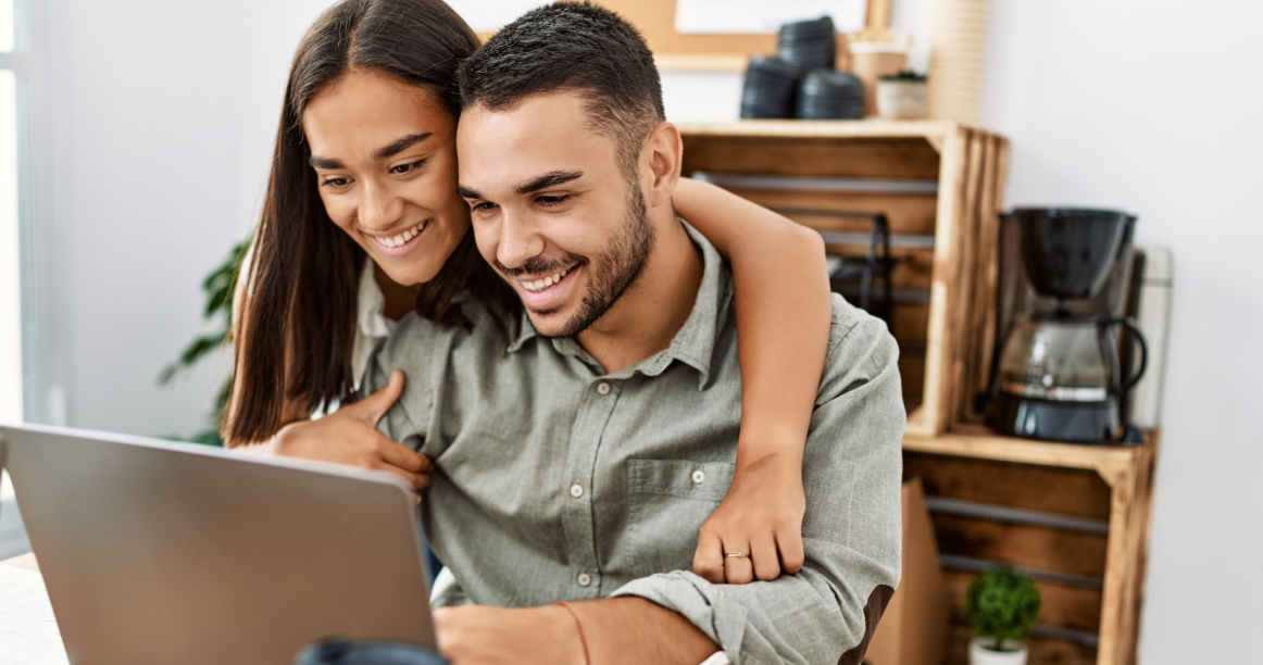 Photo of a couple smiling looking at a laptop